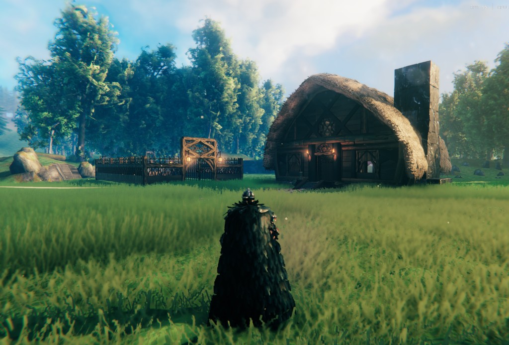Valheim - palisade base around a timber longhouse at sunset in the Meadows (in-game screenshot)